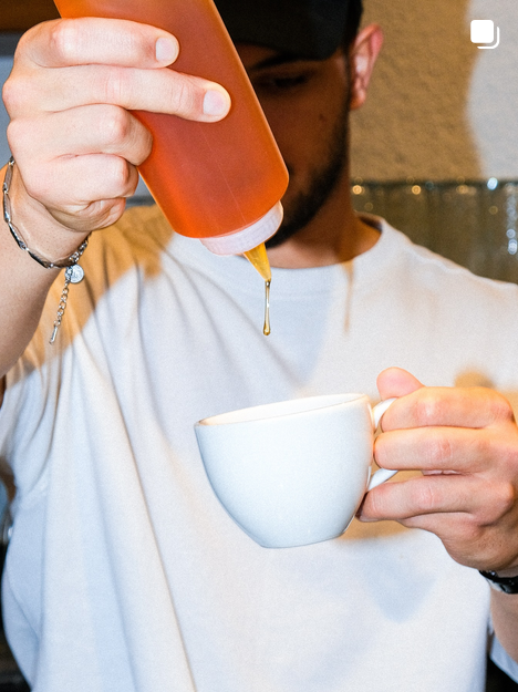 Baristanın fincana karamel şurup damlatması